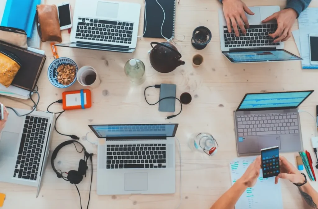 Collaborative workspace with multiple laptops and gadgets.