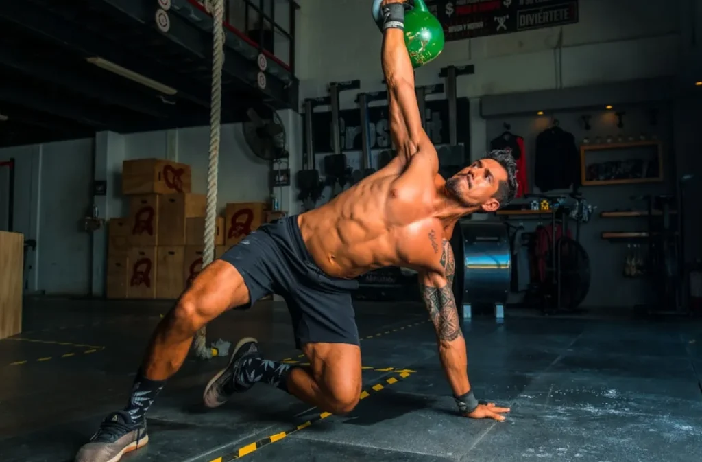 Man practicing Tai Chi with a kettlebell in a gym.