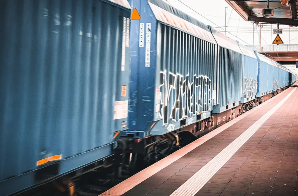 Freight train with blue cargo containers at a station.