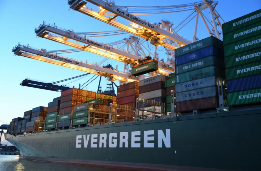 Fire shipping containers under cranes at dusk