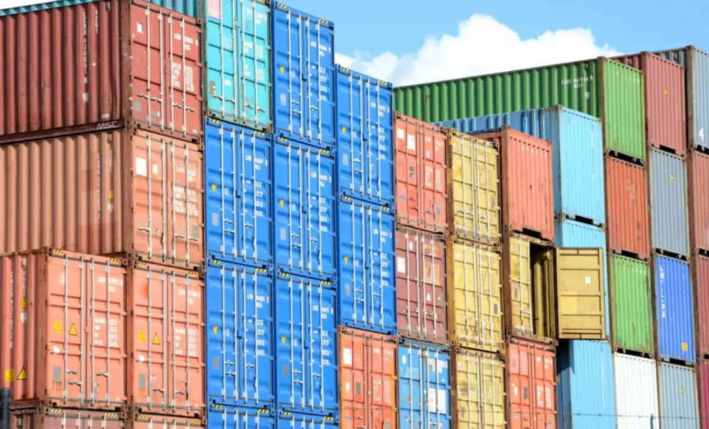 Stacked shipping containers in various colors at the dock.