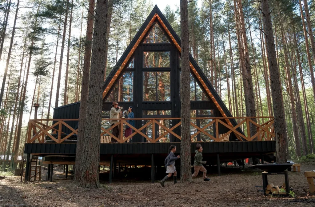 Modern A-frame shipping container cabin in a pine forest.