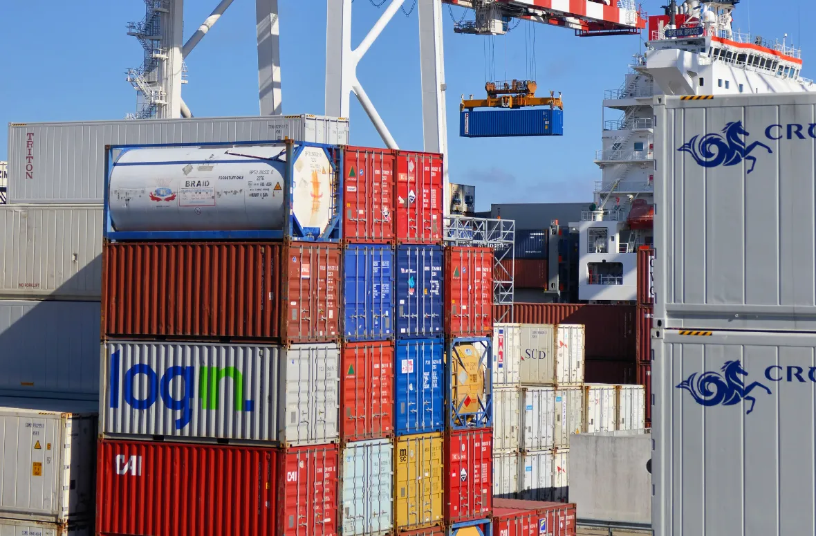 Port crane lifting a ventilated blue container.